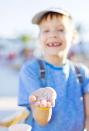 Happy young boy showing a tooth he has just lost. The tooth in a hand in focus.の写真素材