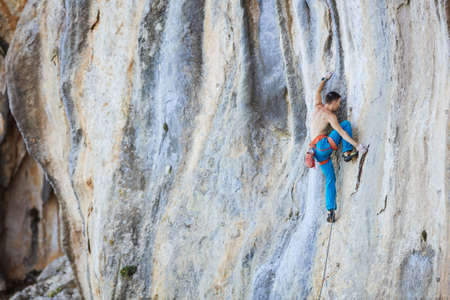 Caucasian young man climbing challenging route on cliff