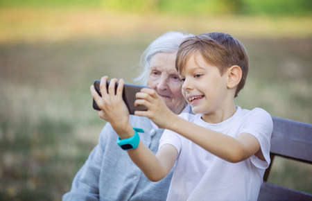 Young boy and his great grandmother using smartphone to take selfie. Making video call. Mobile internet.の写真素材