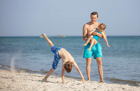 Father, his little daughter and son having fun on the beachの写真素材