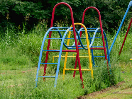 Playground equipment in a deserted park where plants grow