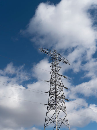 View of power transmission tower and blue sky from below