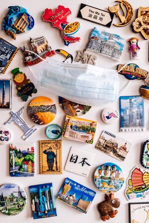 Many magnets on fridge showing several countries on face COVID protection maskの写真素材