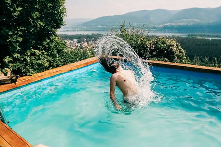SIBERIA, RUSSIA - JULY 19: Man with long hair jumping from water at swimming poolの写真素材