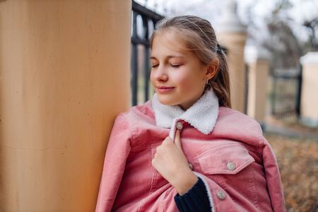Young girl teenager with shut eyes. Teen standing in park smiling and thinkingの写真素材