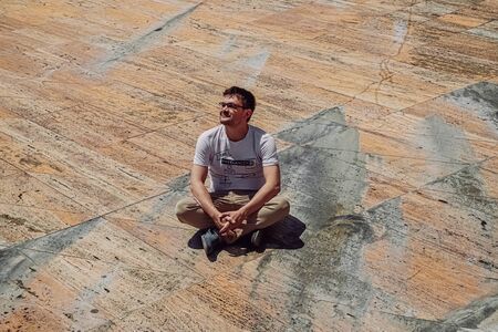 Freelancer man sitting on stone surface. Marble floor with people near concert hall Casa da musica in Porto, Portugalの写真素材
