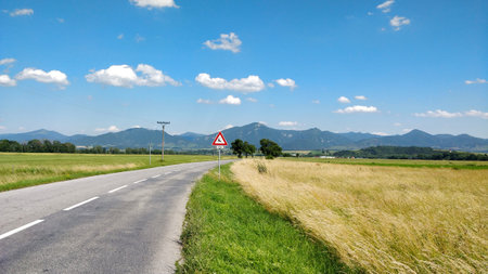 Road in the countryside of Slovakia with mountains in the background going through agriculture are during beautiful Summer day.の写真素材