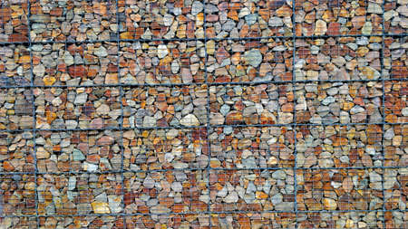 Wall made of beautiful colorful stones. Outer side is made of metal bars. The wall is used as an architectural element. The wall is approximately three meters high.の写真素材