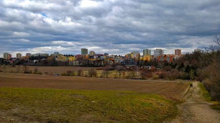 Fields in the suburbs of Czech city Prague. In the background stands residential area made of block of flats. The sky is dark and it might rain anytime soon.の写真素材