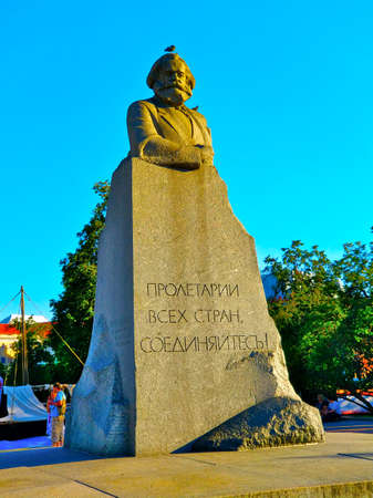 Statue of Carl Marx in Moscow, Russia, with bird sitting on statue's head during summer day.のeditorial素材