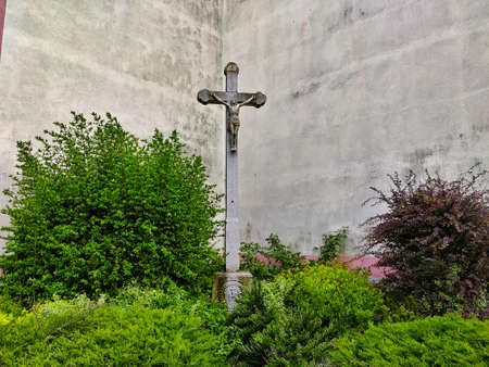 Crucifix standing outside of the church wall in the little green garden.の写真素材
