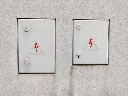 White wall with two doors for electrical distribution grid maintenance entrance. Both doors have a...