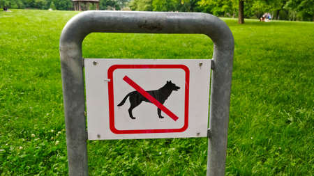 Sign dogs not allowed into this park. The sign is located in one local parks in Prague, Czech Republic. There is a large grass area in the background.の写真素材