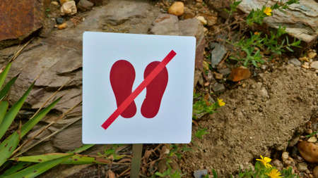 Symbol of a crossed feet situated in the garden. The symbol means do not step on the grass.