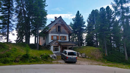 Grobming, Austria - August 15, 2021: Wooden mountain chalet standing on the forest hill by the road with a car being park next to it.のeditorial素材