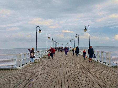 Sopot, Poland - August 27, 2021: Wooden walking wharf with lamps on each side and a lot of people walking around and taking pictures. The weather is cloudy.のeditorial素材