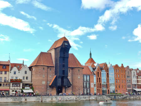 Gdansk, Poland - August 26, 2021: Black wooden medieval crane building on the Gdansk waterfront. The building is surrounded with traditional Gdansk hanseatic houses.のeditorial素材