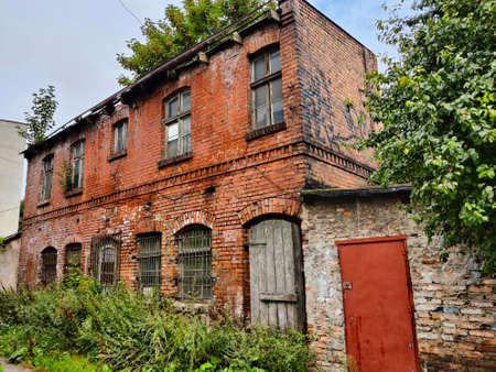 Gdansk, Poland - August 27, 2021: Old desolated house in Gdansk outskirts completely overgrown with grass. The wall has traditional brick style design.のeditorial素材