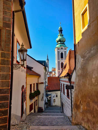 Cesky Krumlov, Czech Republic - September 4, 2021: Narrow street going from the castle into the old town passing by the medieval municipal houses. There is also a church tower on the horizon.の写真素材