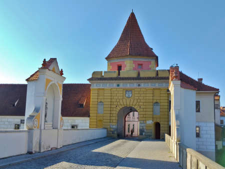 Cesky Krumlov, Czech Republic - September 4, 2021: Historical entrance gate into the old town of Cesky Krumlov. The gate is yellow and the road is made of cobblestones.のeditorial素材
