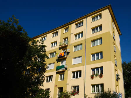 Prague, Czech Republic - September 25, 2021: Yellow facade block of flats with dark blue sky in the background in Prague's Hloubetin district.のeditorial素材
