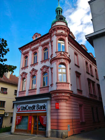 Benesov u Prahy, Czech Republic - September 28, 2021: Pink of municipal corner building in the city center with small bank office in the ground floor.のeditorial素材