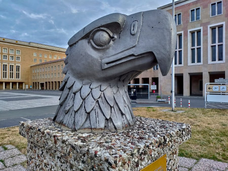 Berlin, Germany - July 6, 2022: Iron statue of an eagle's head standing on the massive stone block in front of the Tempelhof airtport.のeditorial素材