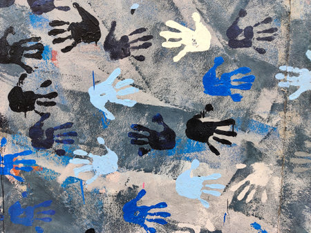 Berlin, Germany - July 6, 2022: Detail of Berlin wall with painted hands on it. The hands are blue black and one is yellow.のeditorial素材