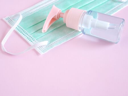 The alcohol gel in the bottle pump with a protective face mask on a pink background. Health concept with copy space. Top view, Flat lay.の写真素材