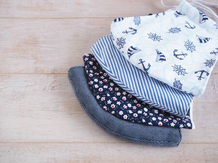 Blue tone fabric face mask to prevent pollution and viruses. DIY handmade from cotton muslin on white wooden background. Healthcare and New normal concept. Copy space for your text.の写真素材