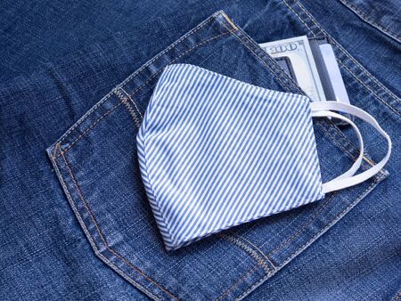 White and blue striped fabric face mask DIY handmade from cotton muslin to prevent pollution and viruses with money clip on blue jeans background. Healthcare and New normal concept.の写真素材