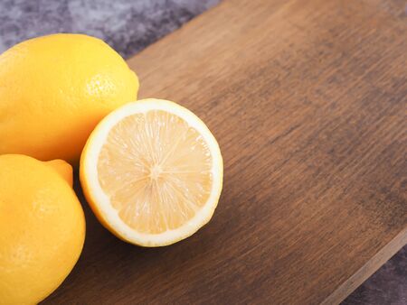 Lemons fruit on wooden cutting board have a dark grey background is a good source of Vitamin C, which helps control weight and Reduce Cancer risk. Copy space for text.の写真素材