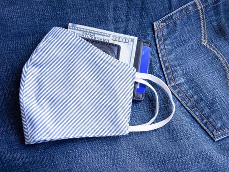 A blue and white striped fabric face mask with money clip on jean background. Every time leaving the house must be used to prevent pollution and viruses. Healthcare, New normal concepts.の写真素材