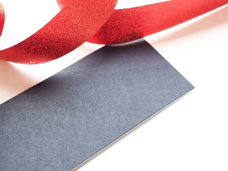 Red ribbon, spiral coil with blue tag on white paper background with copy space.の写真素材