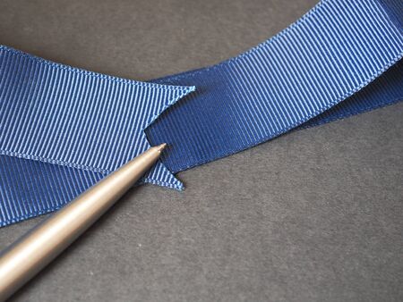 Blue ribbon with a pen on black paper background with copy space.の写真素材