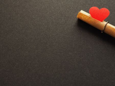Red paper heart plugging paper message roll on black background. Copy space for your text.の写真素材