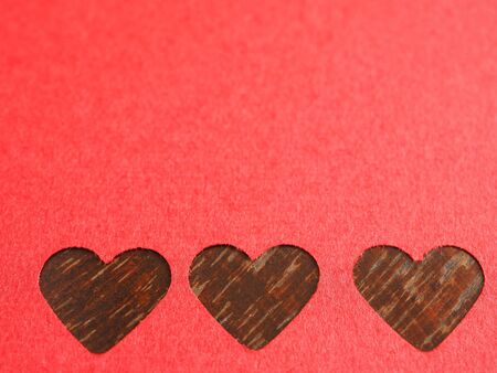 Close up, red paper punching in a heart shape, placed on  wooden for the background of your text. The concept for design, wallpaper, loveの写真素材