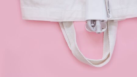 Reusable grey silicone drinking straws and a cleaning brush in the white box with a hanger, fabric bag on pink background, top view, eco-friendly lifestyle. Zero waste concept.の写真素材