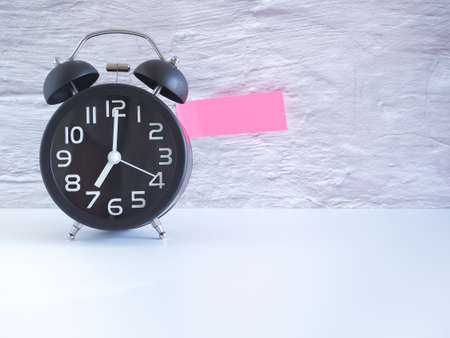 The black clock  pink note on white background, Copy space for your text.の写真素材