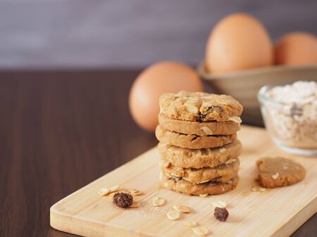 Stack healthy homemade oat cookies on wooden boards with egg over brow wooden background.の写真素材