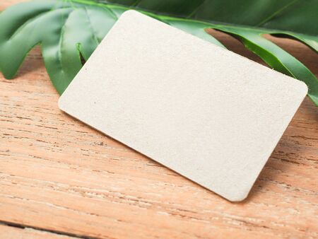 Empty brown paper decorated with green leaves space for text on a wooden table with copy space.の写真素材
