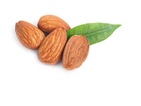 A pile of almonds seed and half with leaves isolated on a white background.の写真素材