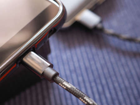 The smartphone is charging the power bank on a blue background. Copy space.