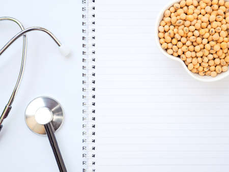 Soybeans in a heart-shaped bowl and stethoscope on a notebook, Healthy food concept. Plant protein. Top view with copy space.の写真素材