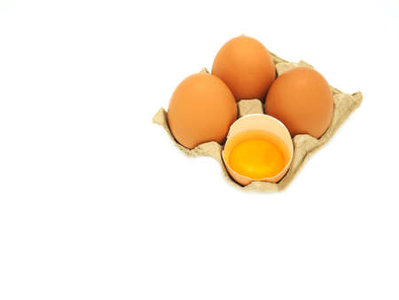 A group of eggs and fresh half-cracked egg in brow paper tray isolated on white background. High protein and vitamins, Concept of healthy.の写真素材