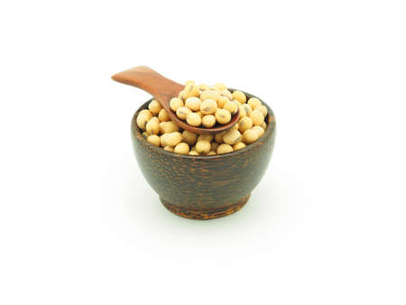 Soybeans in wooden spoon over wooden bowl isolated on white background.の写真素材