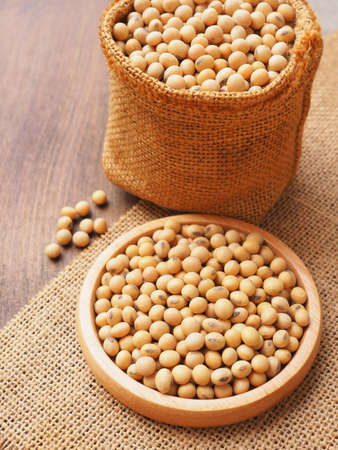 Soybeans in wooden plate and sackcloth bag on sackcloth background, Protein plant health food.