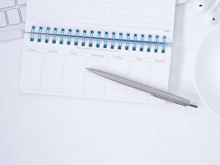White workplace desk table with monthly notebook and pen, earphones. Top view with copy space for...