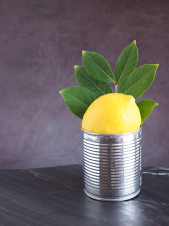 Lemons fruit and leaves in a tin can put on a black stone and have a dark grey background is a good source of Vitamin C, which helps control weight and Reduce Cancer risk.の写真素材