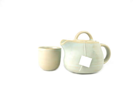 Ivory color ceramic teapot and cup with a tea bag inside and white label isolated on a white background, Asian food concept with copy space.の写真素材